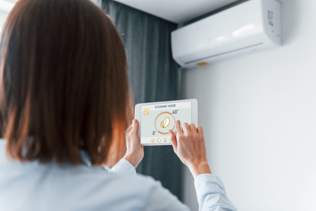 Modern technologies Rear view of woman that is indoors controlling smart home